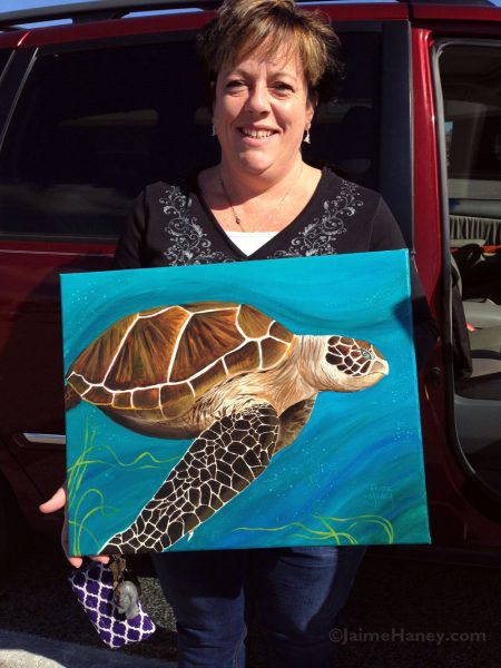 Collector holding a commissioned painting of a swimming sea turtle.