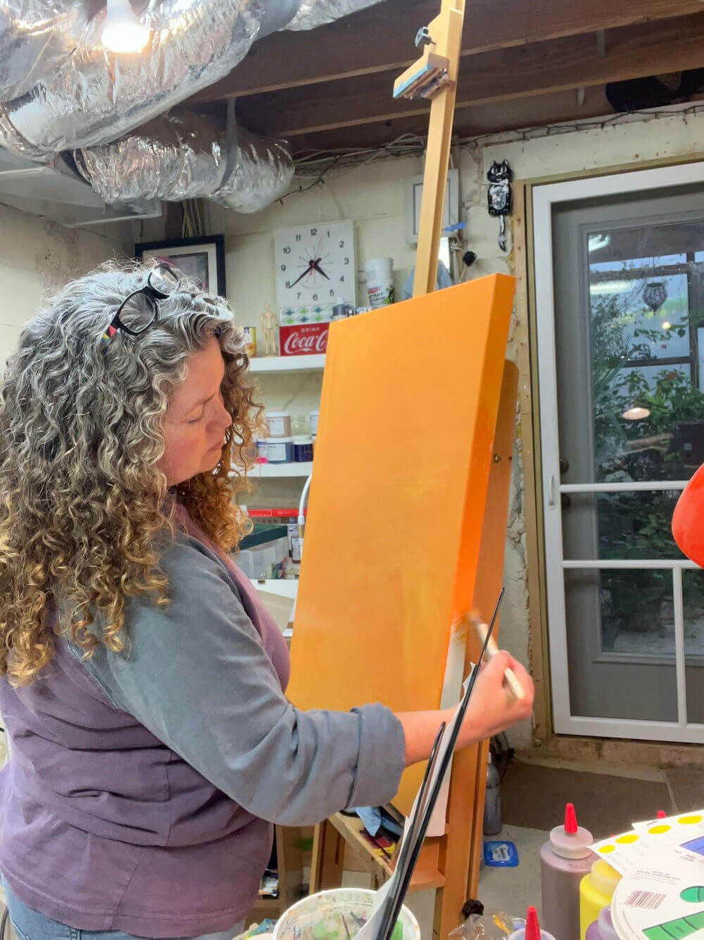Jaime Haney painting a canvas orange in her art studio.